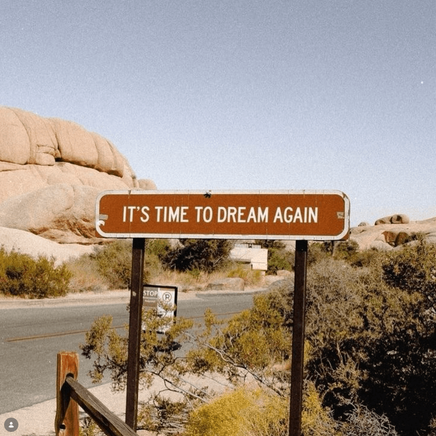 It's Time to Dream Again road sign in golden desert landscape