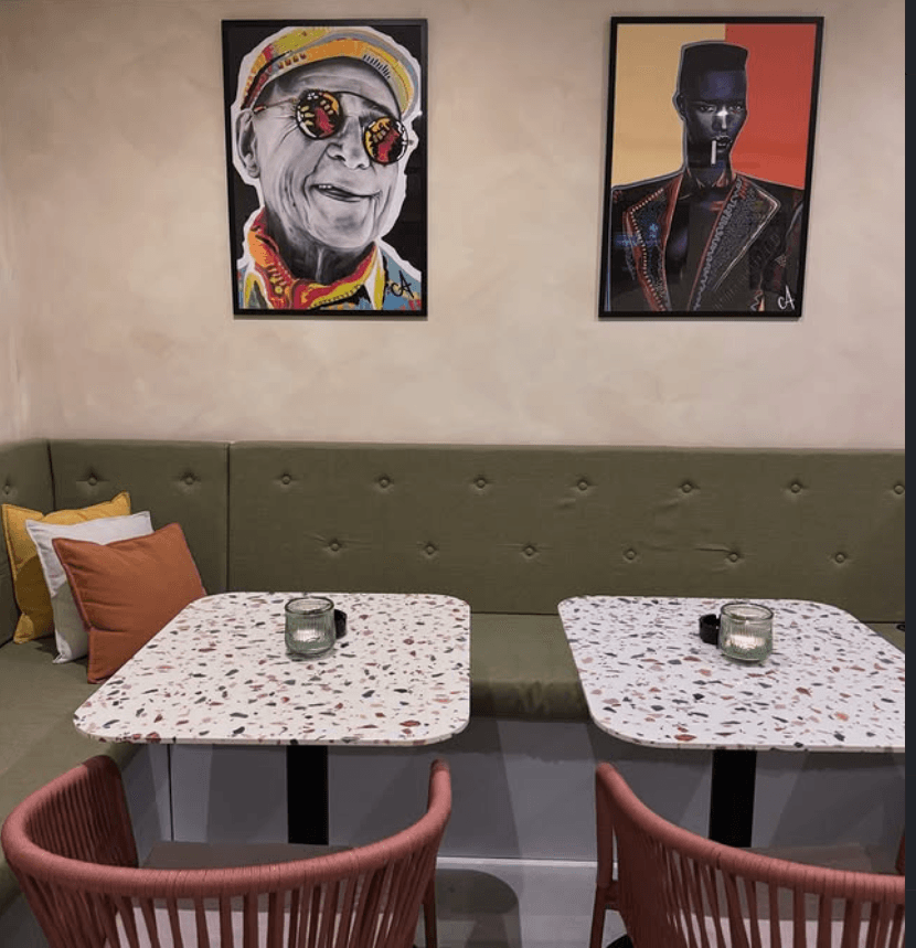 The Bakery interior with olive banquette seating, terrazzo tables and colorful art