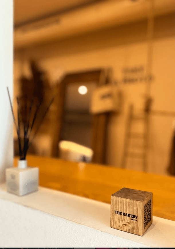 The Bakery branded wooden QR block with warm bokeh interior